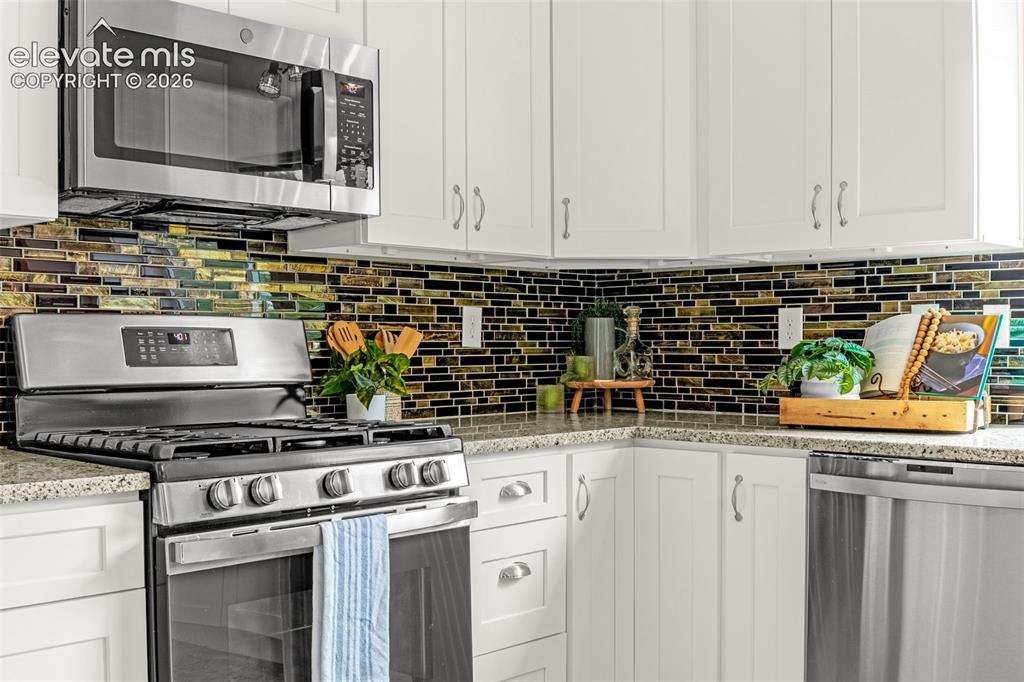 Image 3 of 44: Modern kitchen featuring white cabinetry, stainless steel appliances, a mos