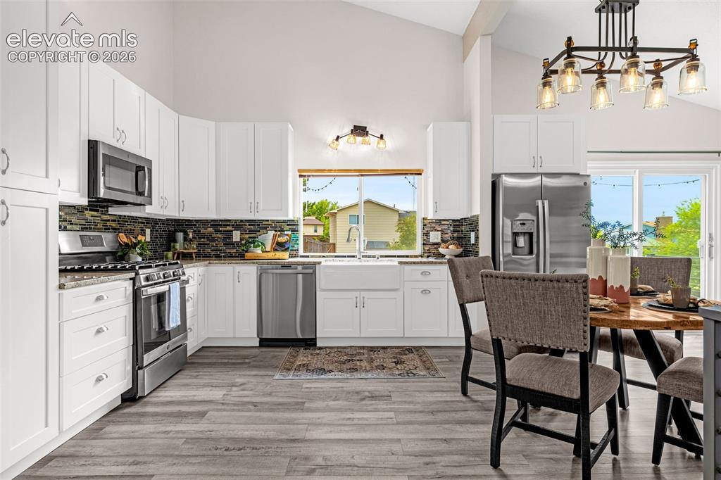 Image 5 of 44: Open-concept kitchen and dining area featuring vaulted ceilings and luxury 