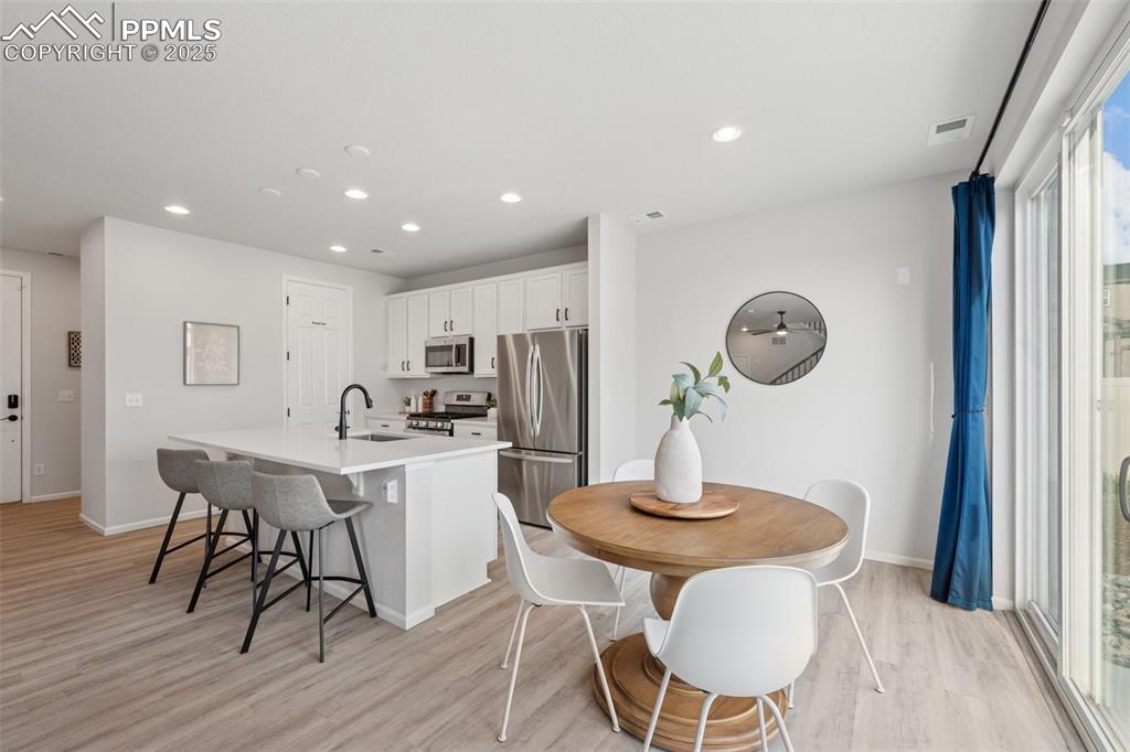Image 10 of 30: Kitchen featuring a kitchen island with sink, light wood-style floors, appl