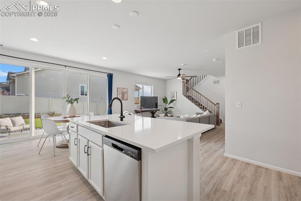 Image 12 of 30: Kitchen featuring dishwasher, light wood-type flooring, white cabinets, rec