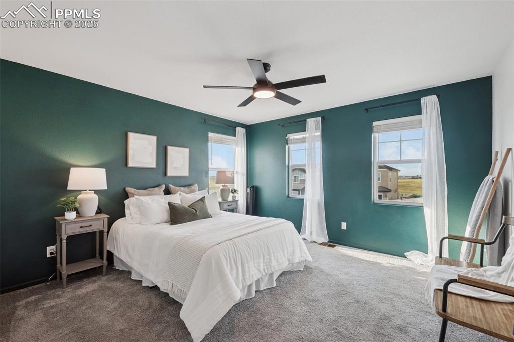 Image 16 of 30: Bedroom featuring dark colored carpet, multiple windows, and a ceiling fan