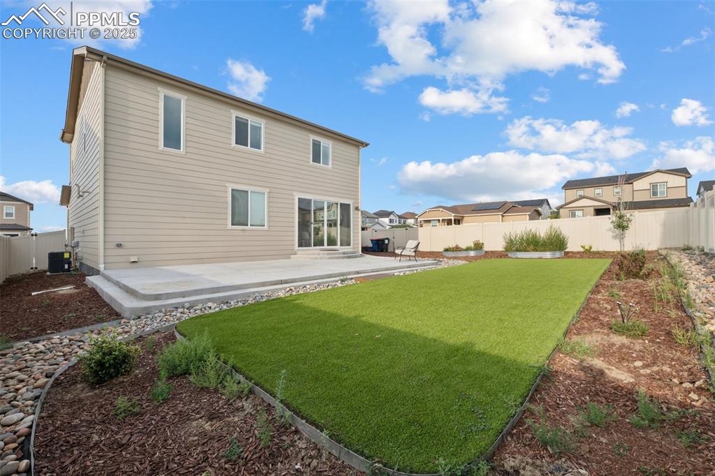Image 26 of 30: Back of property with a fenced backyard, a patio area, turf and a residenti