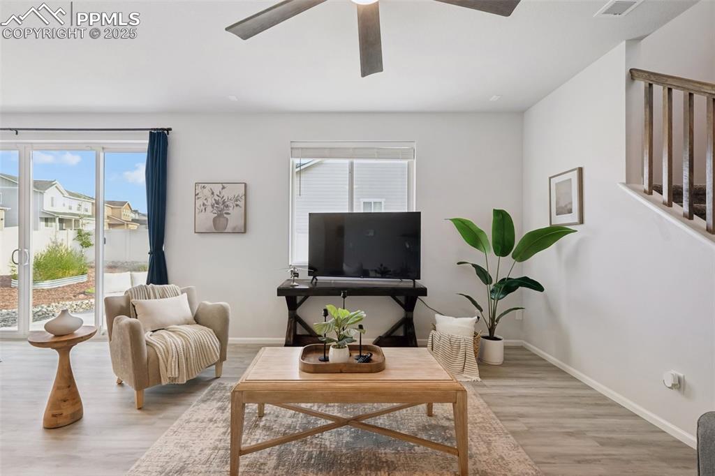 Image 5 of 30: Living area with light wood finished floors and ceiling fan