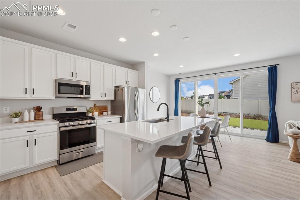 Image 7 of 30: Kitchen with appliances with stainless steel finishes, light wood-style flo