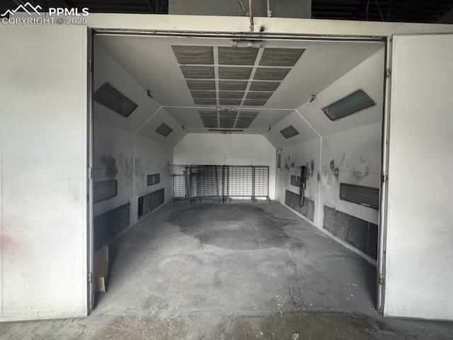Image 8 of 9: garage, unfinished concrete floors, and vaulted ceiling