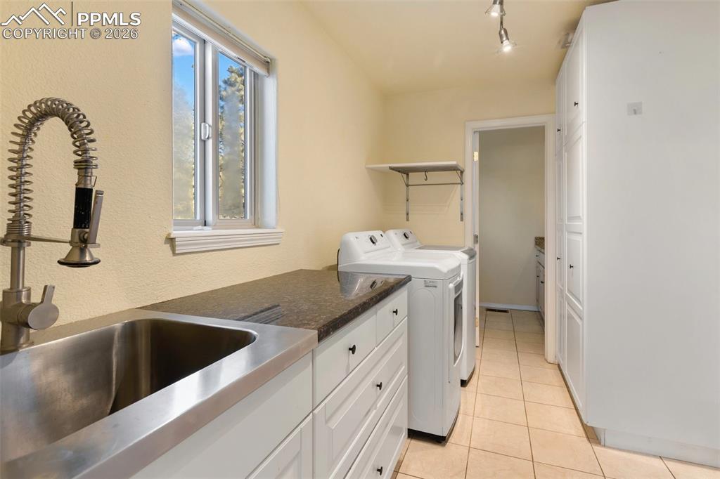 Image 12 of 36: Laundry area with washer and dryer, light tile patterned floors, and track