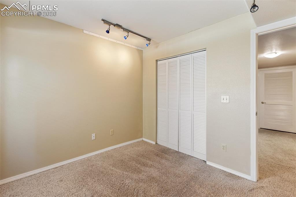 Image 13 of 36: Unfurnished bedroom with rail lighting, carpet flooring, and a closet