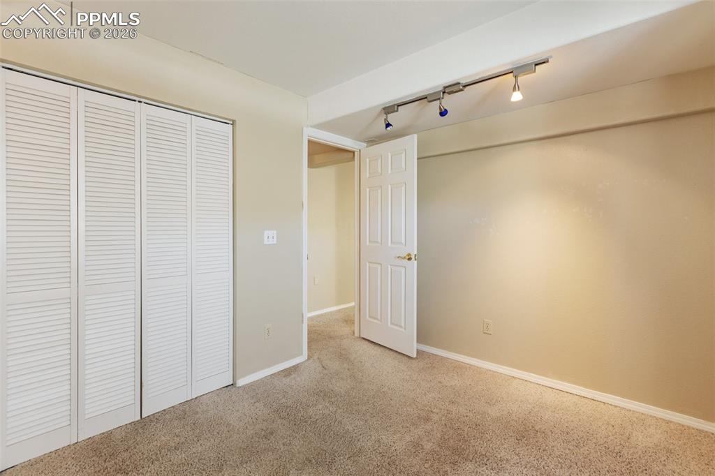 Image 14 of 36: Unfurnished bedroom featuring rail lighting, carpet flooring, and a closet