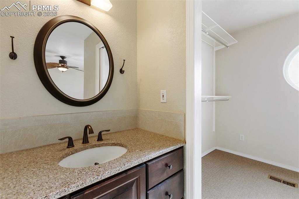 Image 19 of 36: Bathroom featuring vanity, light colored carpet, a walk in closet, and ceil