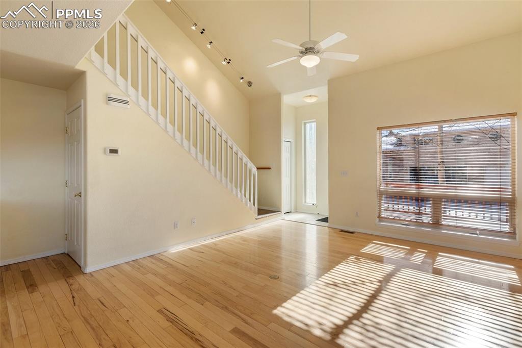 Image 6 of 36: Unfurnished living room with a towering ceiling, light wood-style floors, s