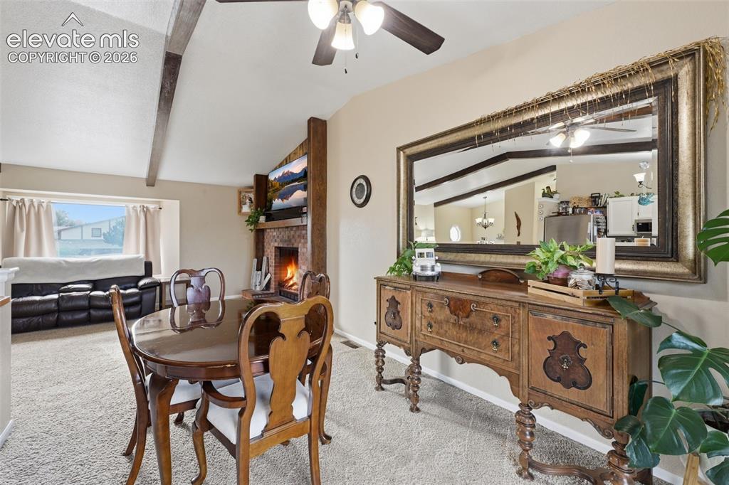 Image 10 of 28: Vaulted ceilings with exposed wood beams, a fireplace with a stone-tile sur