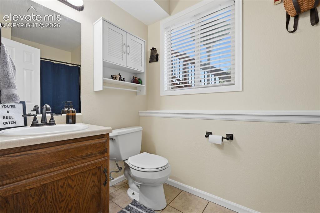 Image 22 of 28: Bathroom featuring a wood-finish vanity with a built-in sink, white cabinet