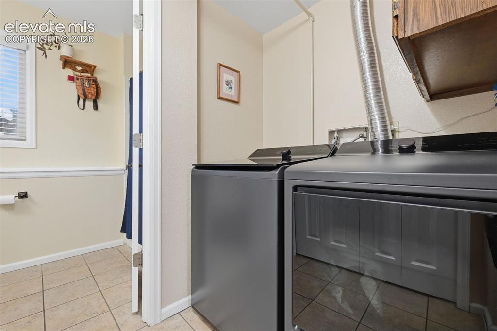 Image 24 of 28: Laundry area featuring tile flooring, white baseboards, and wainscoting