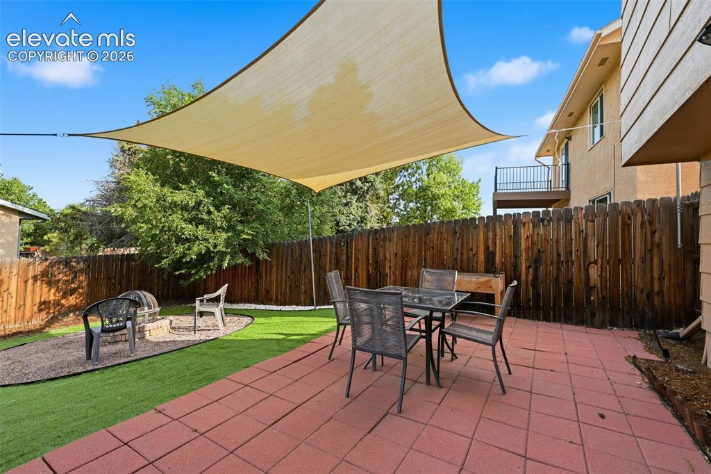 Image 25 of 28: Expansive backyard featuring a large red paver patio, artificial turf, and