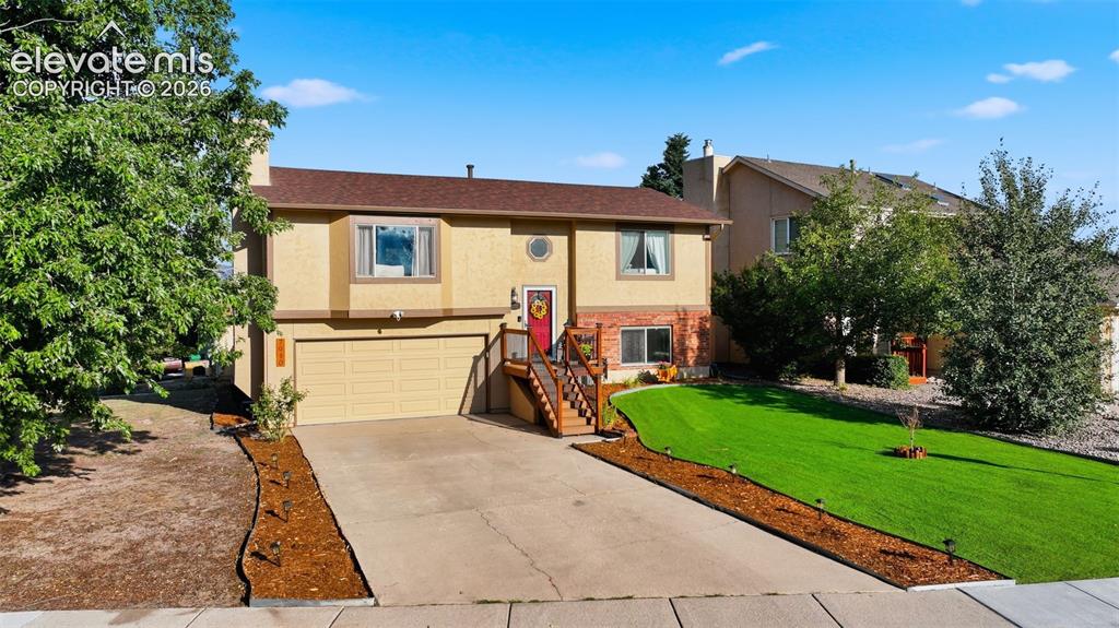 Image 27 of 28: Split-level residence featuring a two-car garage, concrete driveway, and a