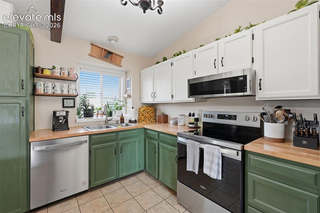 Image 5 of 28: Kitchen featuring two-tone cabinetry with white upper and green lower cabin