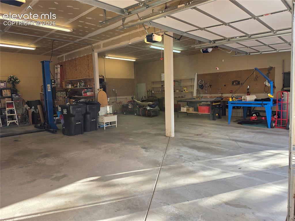 Image 29 of 38: Large garage space with a concrete floor, overhead lighting, and exposed ce