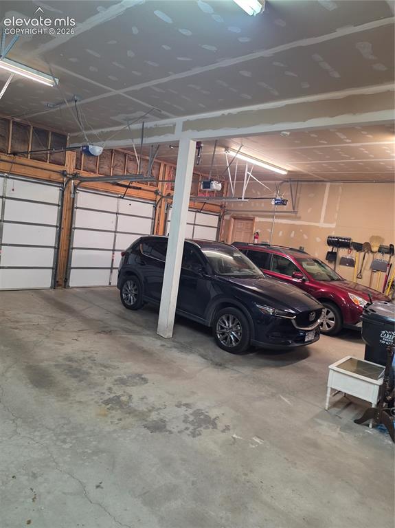 Image 33 of 38: Three overhead garage doors with automatic openers, concrete flooring, and 