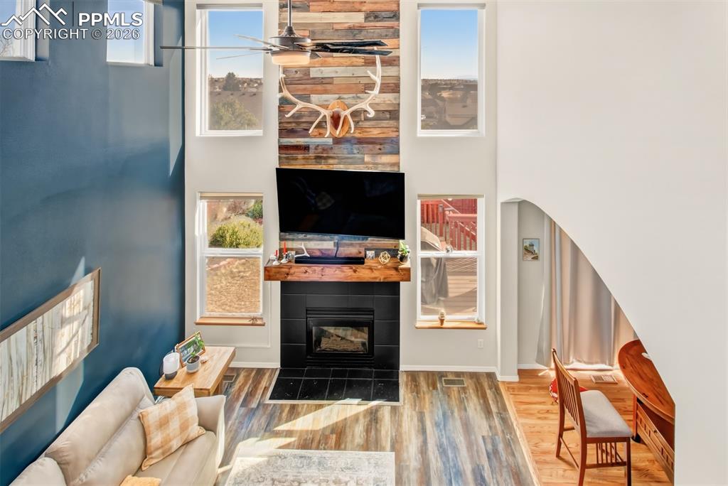 Image 16 of 45: Living room with gas burning fireplace, custom mantle, a wall of windows fo