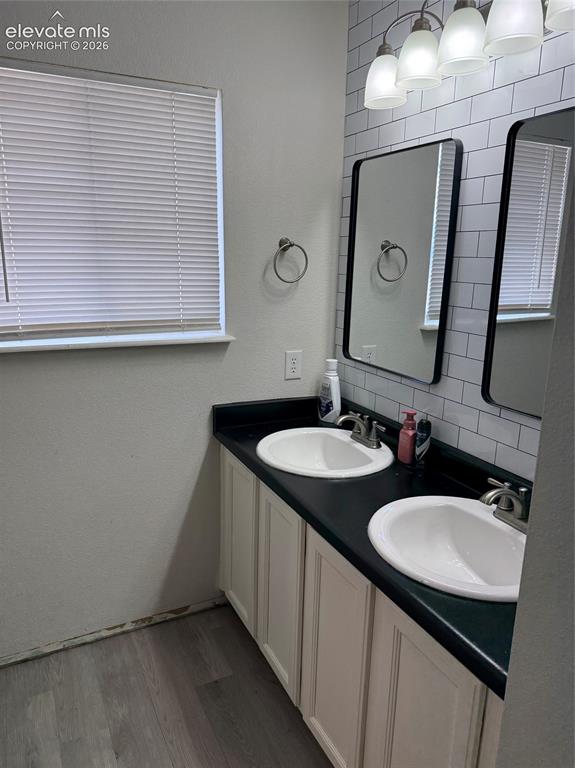 Image 12 of 21: Dual vanity with white cabinetry, black countertop, and two undermount sink