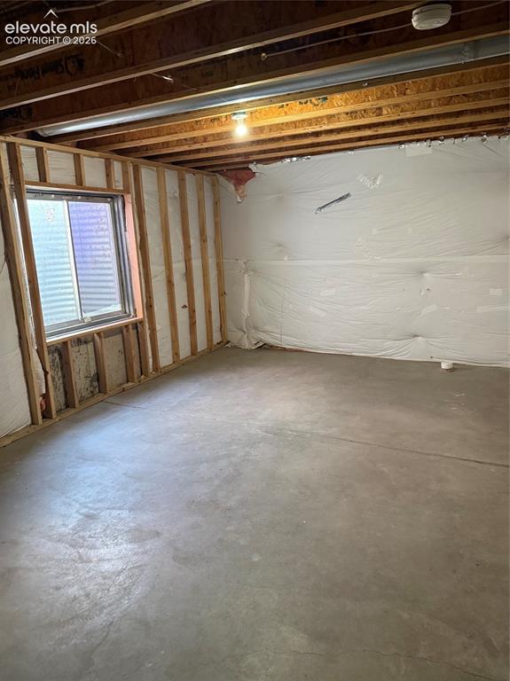 Image 16 of 21: Concrete flooring with exposed ceiling joists and a single-pane window