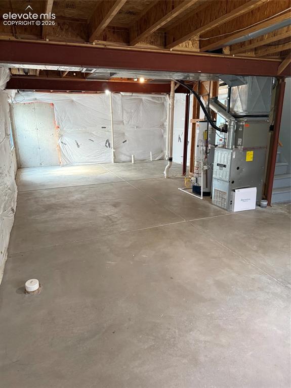 Image 17 of 21: Unfinished lower level with exposed ceiling joists and concrete flooring