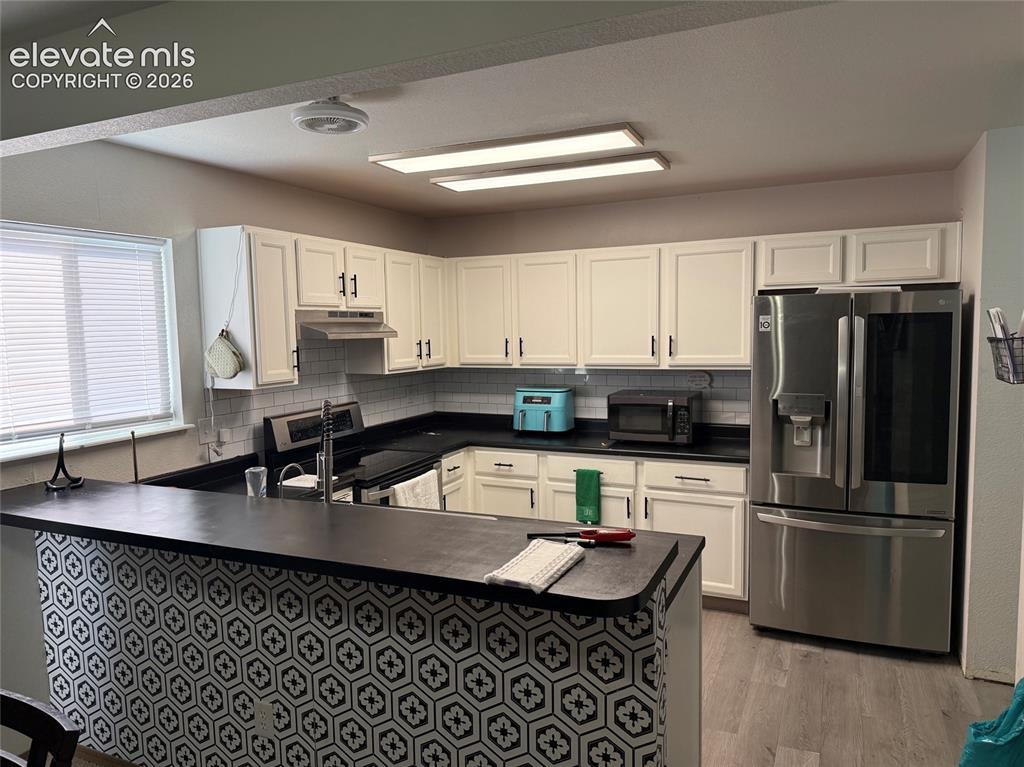Image 5 of 21: White cabinetry, dark countertops, subway tile backsplash, stainless steel 