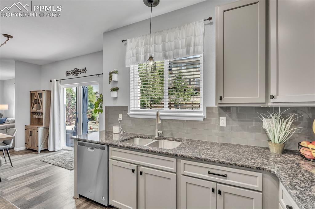 Image 10 of 50: Kitchen with tasteful backsplash, dishwasher, wood finished floors, pendant