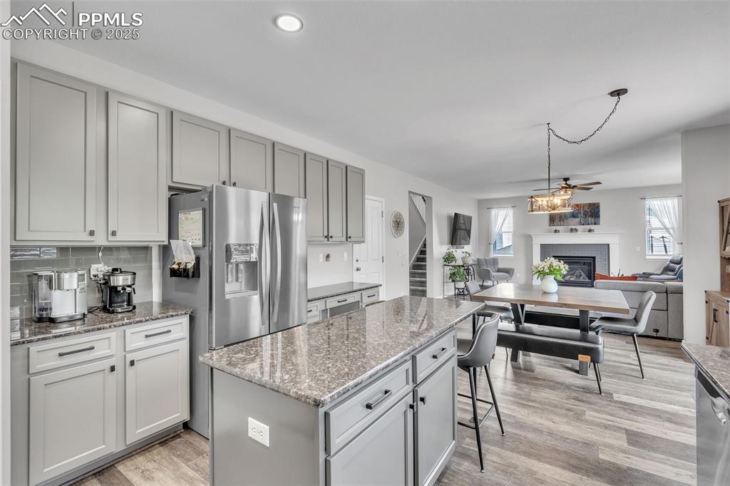Image 11 of 50: Kitchen featuring gray cabinetry, a fireplace, dark stone counters, a cente