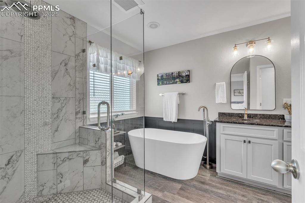 Image 25 of 50: Bathroom with a marble finish shower, a freestanding tub, vanity, tile wall