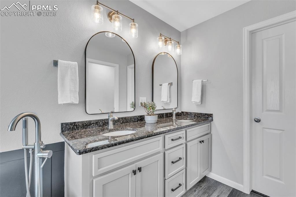 Image 26 of 50: Full bathroom featuring double vanity and dark wood finished floors