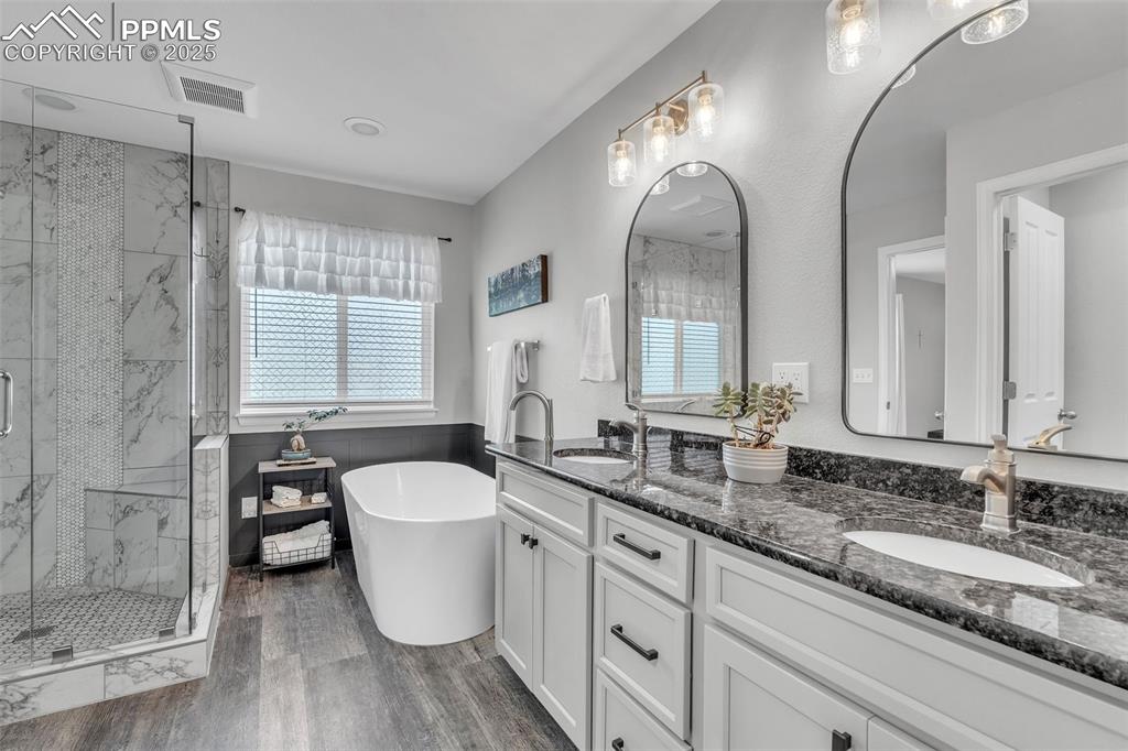 Image 27 of 50: Full bath with a soaking tub, a marble finish shower, double vanity, and da