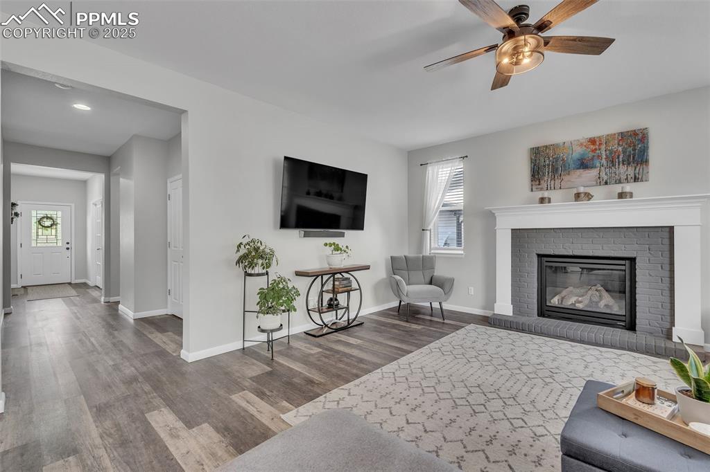 Image 3 of 50: Living room with a fireplace, wood finished floors, and ceiling fan