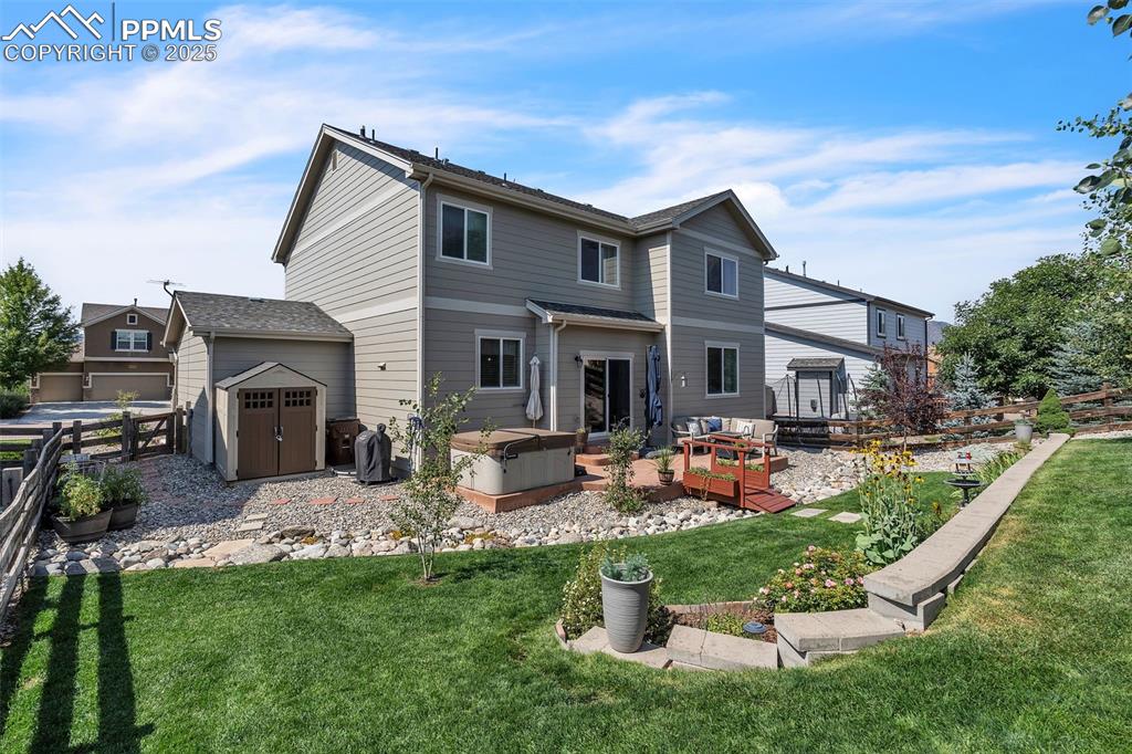 Image 39 of 50: Rear view of property featuring a storage unit, a deck, and a hot tub