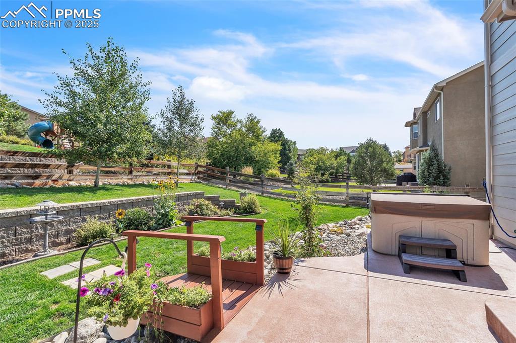 Image 42 of 50: Fenced backyard with a patio and a hot tub