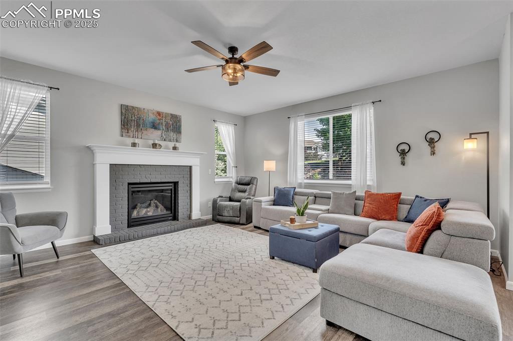 Image 5 of 50: Living room featuring wood finished floors, a fireplace, and ceiling fan