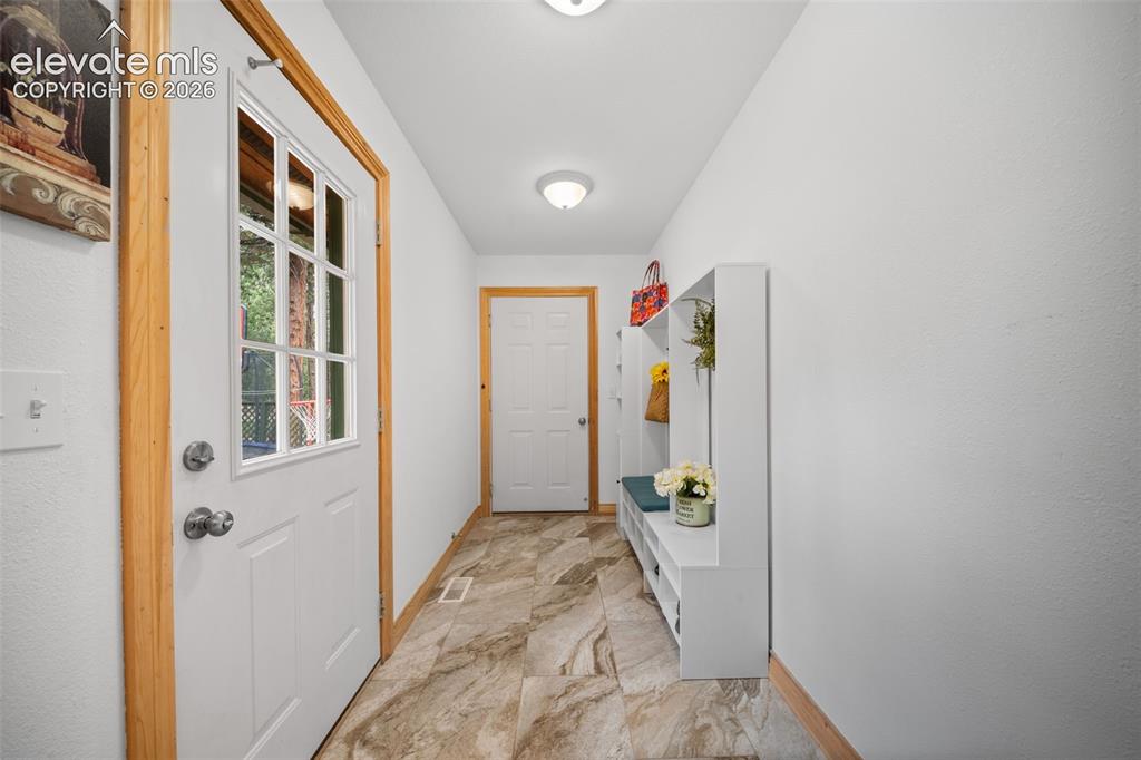 Image 11 of 39: The entry is warm and inviting with natural wood floors, vaulted ceilings a