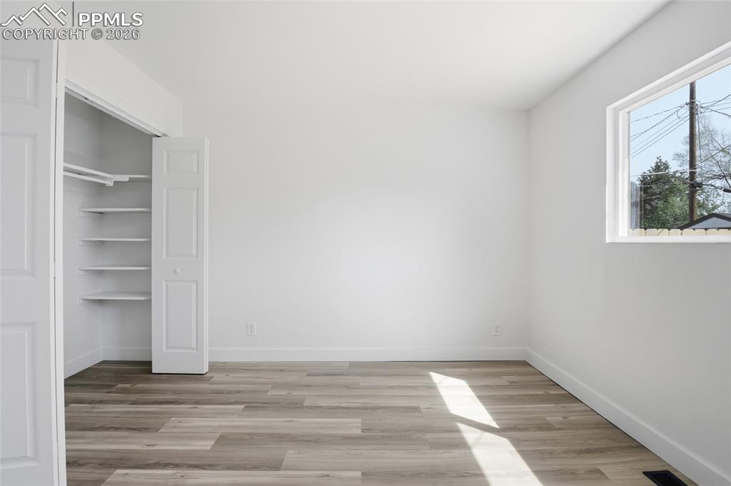 Image 13 of 44: This room features bright white walls, wood-style flooring, and a window pr