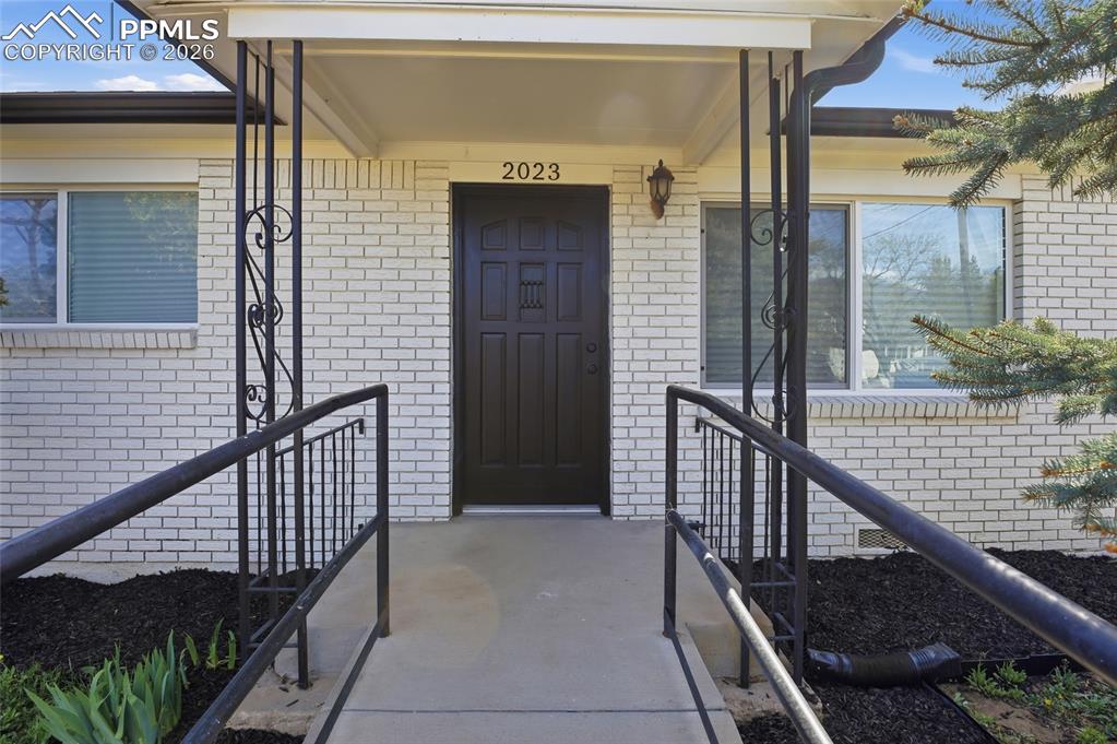 Image 2 of 44: The property features a white brick exterior, a covered entryway, and a dar