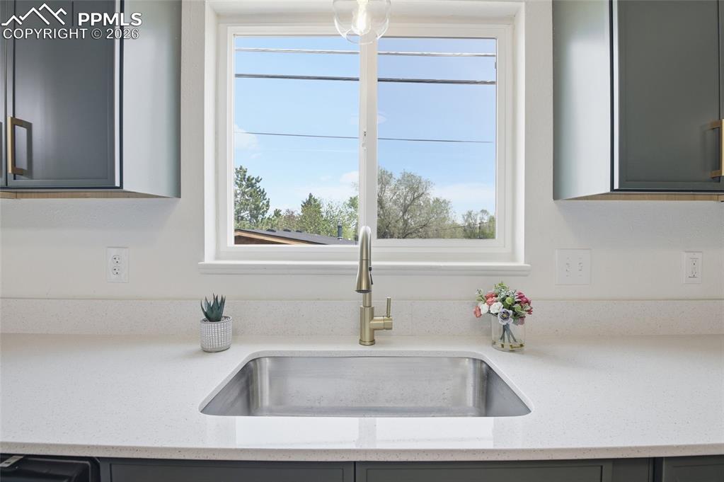 Image 24 of 44: Kitchen sink with a gold-toned faucet, set in a light-colored countertop