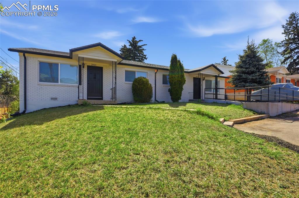 Image 40 of 44: The property features a white brick exterior and a well-maintained lawn