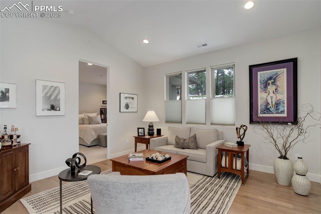 Image 12 of 28: Living area with lofted ceiling, light wood-style floors, and baseboards