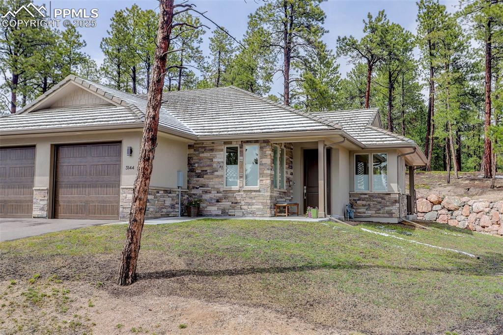 Image 24 of 28: View of front facade featuring stone siding, stucco siding, concrete drivew
