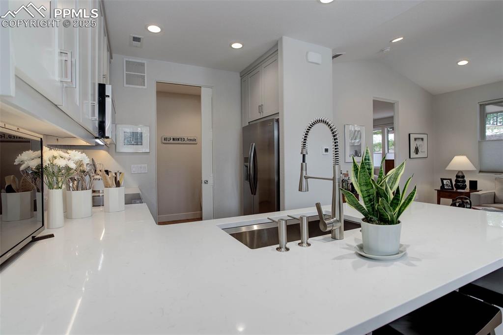 Image 6 of 28: Kitchen with stainless steel fridge with ice dispenser, a sink, lofted ceil
