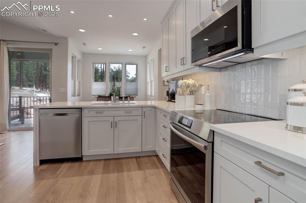 Image 7 of 28: Kitchen featuring stainless steel appliances, a peninsula, light countertop