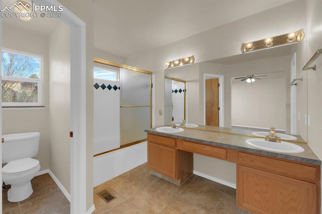 Image 16 of 41: Bathroom featuring combined bath / shower with glass door, double vanity, a