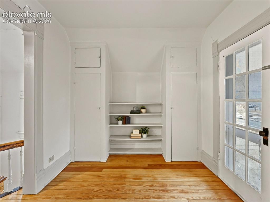 Image 20 of 33: Primary sitting room w/french doors, built-ins, opening to balcony.