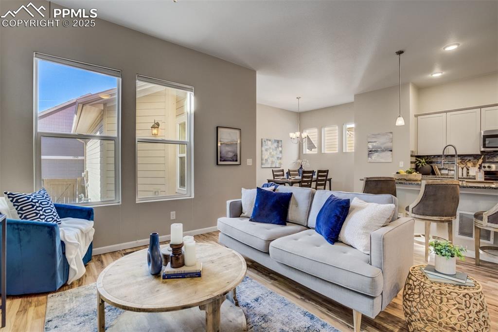 Image 10 of 39: Living room with light wood-style flooring, a notable chandelier, baseboard