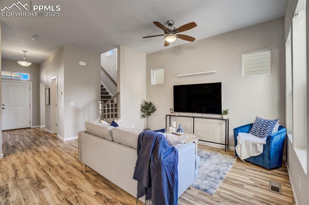 Image 9 of 39: Living room with stairs, baseboards, ceiling fan, visible vents, and wood f