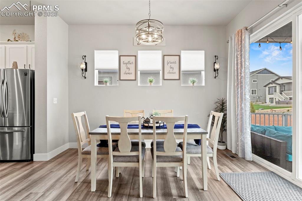 Image 10 of 38: Dining area with a chandelier, light wood-style flooring, and baseboards